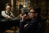 Young man playing poker in a dark bar setting while smoking a cigar
