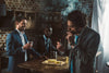 Handsome young businessman smoking a Davidoff cigar while smiling friends drink beverages behind him
