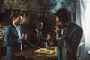 Handsome young businessman smoking a Davidoff cigar while smiling friends drink beverages behind him