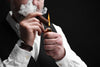 Man lighting a Drew Estate cigar on black background, closeup.