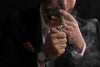 Man lightning Rocky Patel cigar on black background, closeup